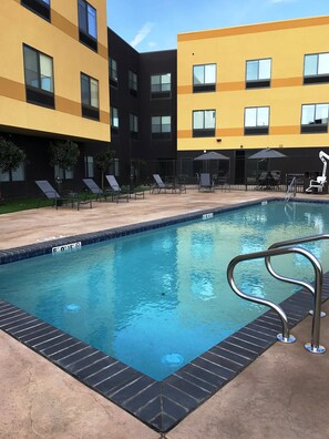 Una piscina al aire libre, sillones reclinables de piscina