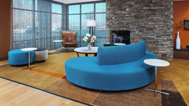 Una sala de estar moderna con un sofá azul, una mesa de centro redonda y una chimenea de piedra.