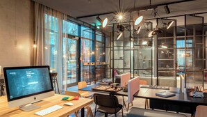 A modern office space with a large desk, computer, and seating area. - Moxy Milan Linate Airport (Segrate)
