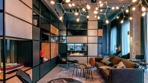 A modern interior with a sofa, chairs, a coffee table, and a fireplace. - Moxy Milan Linate Airport (Segrate)