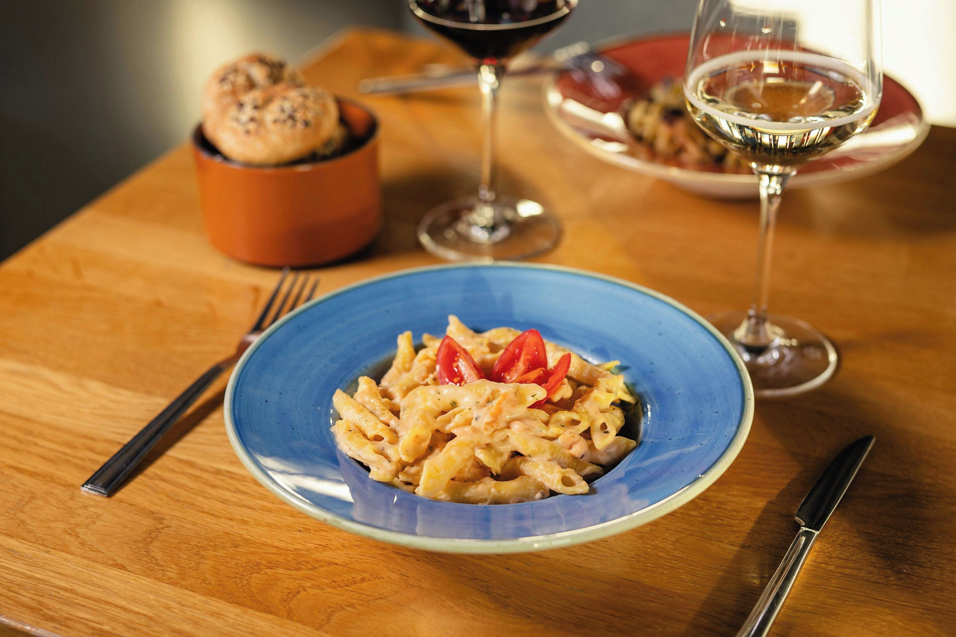 Un plato de pasta con tomates cherry sobre una mesa de madera.