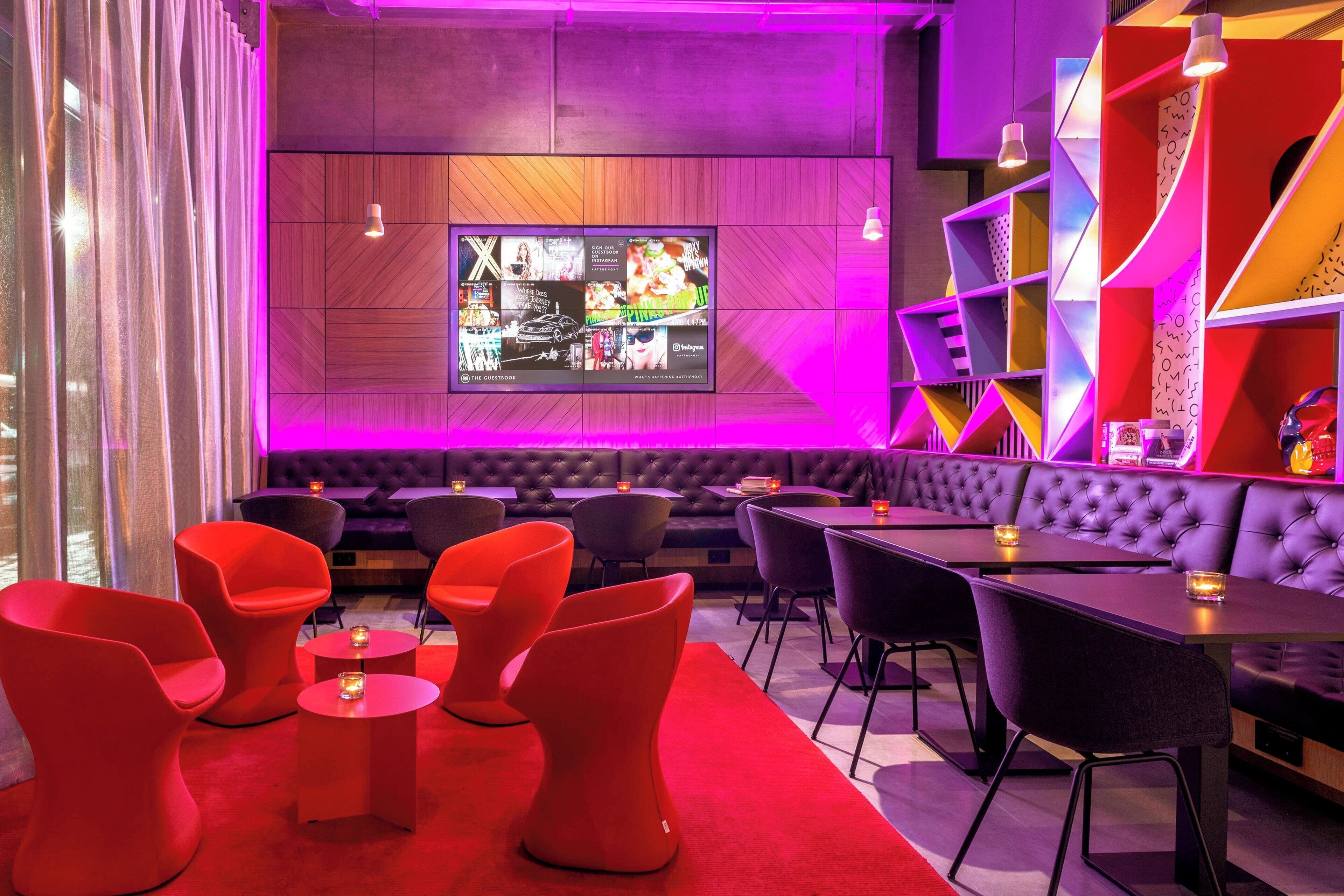 A modern lounge area with a large screen displaying content, comfortable seating, and vibrant decor.