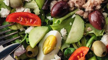 Ensalada con diversos ingredientes, como lechuga, tomates, aceitunas y un huevo duro.
