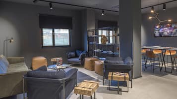 A modern lounge area with sofas, tables, and a bookshelf.