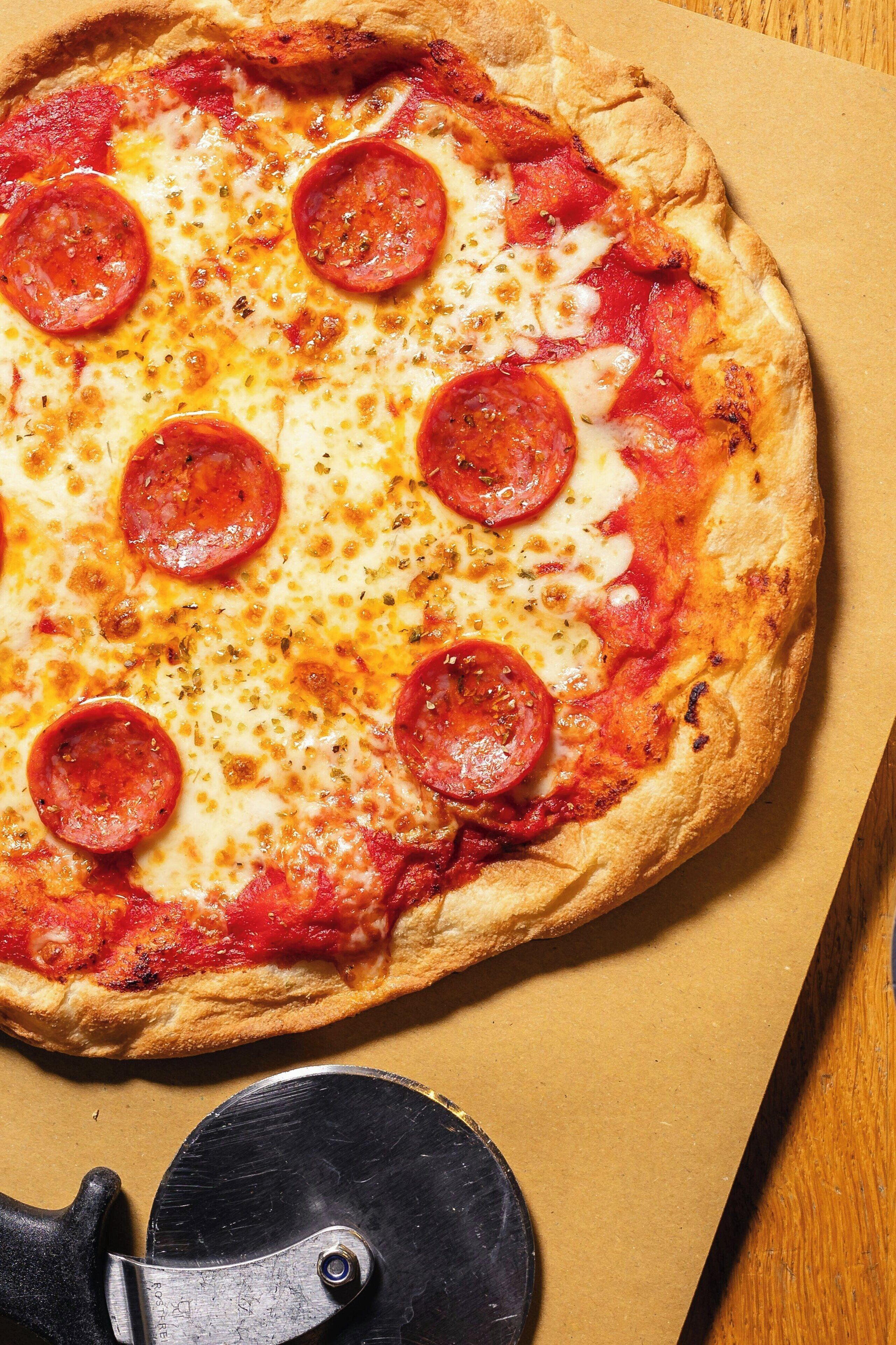 Pizza mit Peperoni auf einer Pappe.