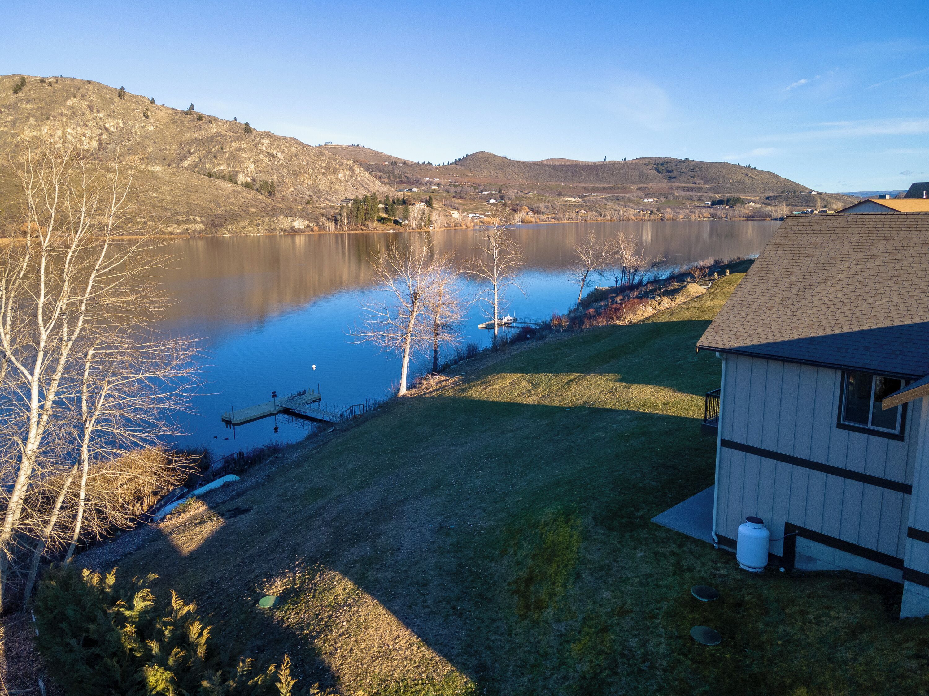 A lakeside property with a dock, a small shed, and a grassy area.