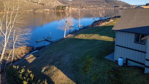 A lakeside property with a dock, a small shed, and a grassy area. - Wapato Lake Retreat-Sleeps 6, Waterfront and dock! (Manson)