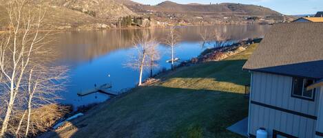 A lakeside property with a dock, a small shed, and a grassy area.