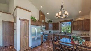 A modern kitchen with wooden cabinets, stainless steel appliances, and a large island with seating. - Wapato Lake Retreat-Sleeps 6, Waterfront and dock! (Manson)