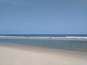 Una playa con cielo despejado y mar tranquilo.