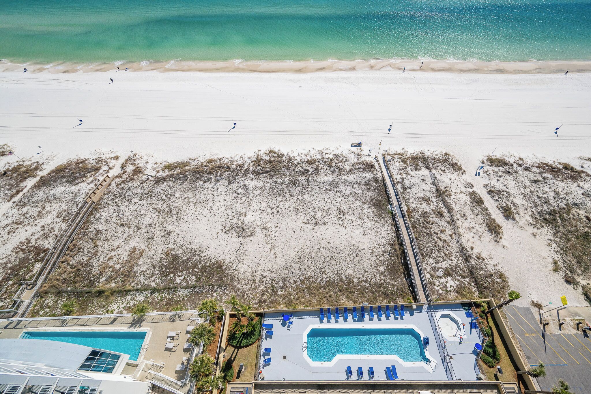 A beach view with a pool area, including a pool, lounge chairs, and a lifeguard stand.