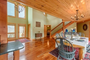 A spacious dining area with a wooden staircase, a chandelier, and a view of the outside. - Family-Style Cabin with Views (Banner Elk)