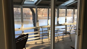Una habitación con vista a un lago, una banca y una mesa con sillas.