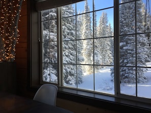 Una stanza con un'ampia finestra che si affaccia su alberi innevati e un cielo sereno.