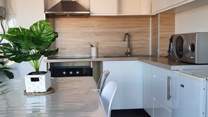 Une cuisine moderne avec des armoires blanches, une hotte de cuisinière en acier inoxydable, un lave-vaisselle intégré et un four à micro-ondes.