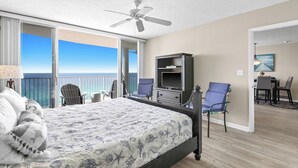 A hotel room with a bed, a TV, a desk, and a chair. There is a balcony with a view of the ocean. - New 1bd w/ OPEN DATES! Sleeps 4 (Panama City Beach)