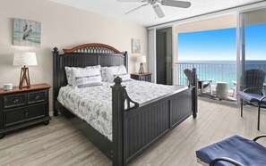 A bedroom with a bed, bedside tables, a ceiling fan, and a balcony with chairs. - New 1bd w/ OPEN DATES! Sleeps 4 (Panama City Beach)