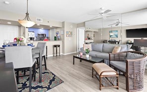 A modern living room with a sofa, coffee table, and a dining area with chairs and a table. - New 1bd w/ OPEN DATES! Sleeps 4 (Panama City Beach)