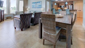 A spacious living area with a dining table, wicker chairs, and a sofa. - Bayside Resort ~ Large Balcony ~ Family Friendly (Miramar Beach)