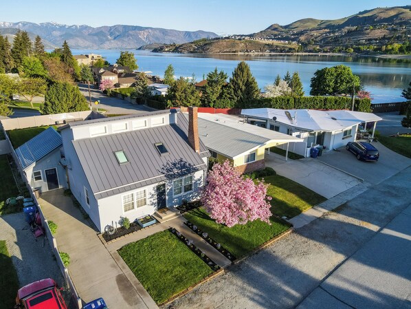 A residential area with houses, a parking lot, and a lake with mountains in the background. - Lake Chelan Vacation Rental with private pool and hot tub, sleeps up to 12 (Chelan)
