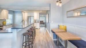 A modern kitchen with a central island, bar stools, and a dining area with benches. - Lake Chelan Vacation Rental with private pool and hot tub, sleeps up to 12 (Chelan)