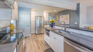 A modern kitchen with stainless steel appliances, white cabinetry, and a central island with a sink. - Lake Chelan Vacation Rental with private pool and hot tub, sleeps up to 12 (Chelan)