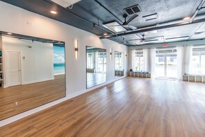 A spacious room with wooden flooring, large mirrors, and a view of the outdoors.