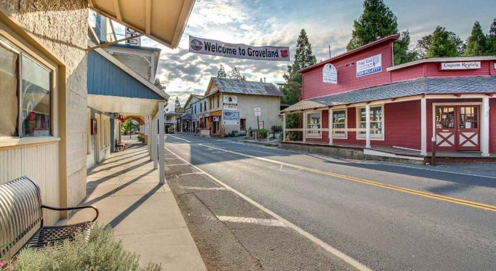 A street view with buildings, a bench, and a 'Welcome to Groveland' sign.
