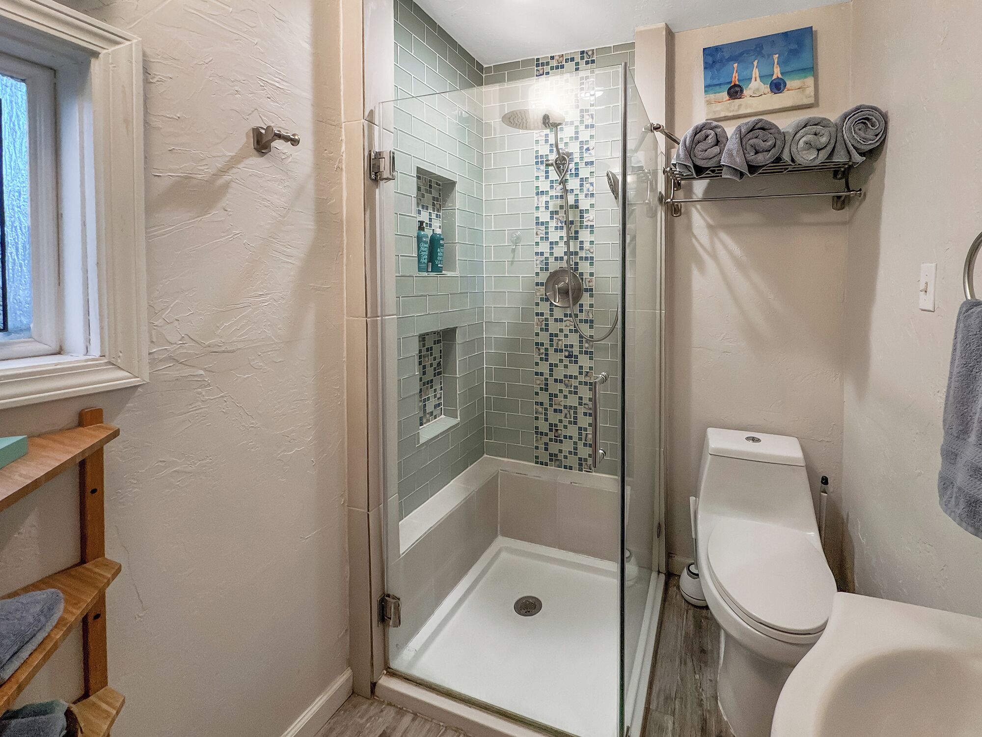 Une salle de bain avec une douche à parois de verre, des toilettes et une étagère avec des serviettes.