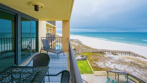 Ein Balkon mit Blick auf den Strand, einen Pool und eine Rasenfläche.