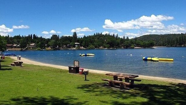 A lakeside park with picnic tables and a canoe on the water.
