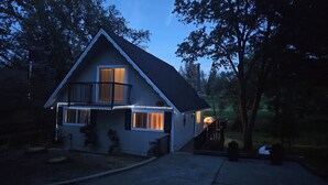 A two-story house with a balcony, a porch with a chair, and a small deck.