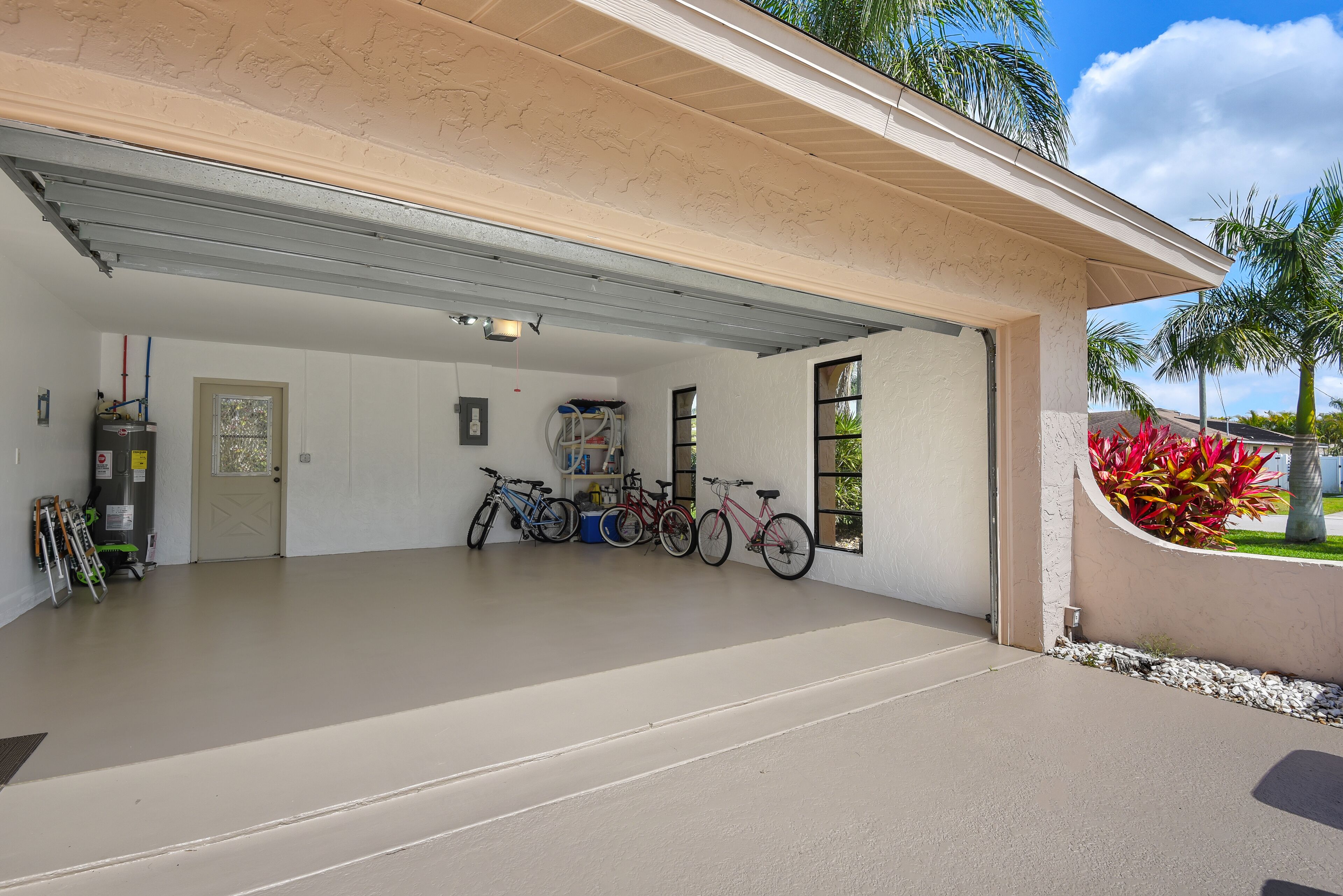 Een garage met een betonnen vloer, een deur en verschillende fietsen erin.