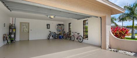 Een garage met een betonnen vloer, een deur en verschillende fietsen erin.