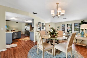 Una cocina amplia con electrodomésticos modernos, un comedor con mesa de vidrio y una sala de estar con candelabro.