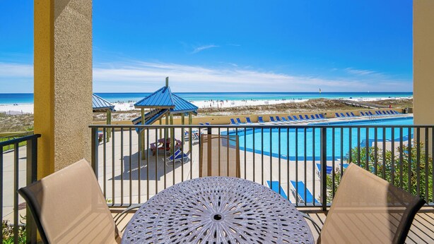 Un balcón con vistas a la playa y a una piscina.