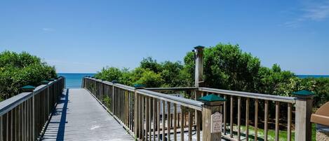 A wooden boardwalk leading to a beach with a clear view of the ocean.