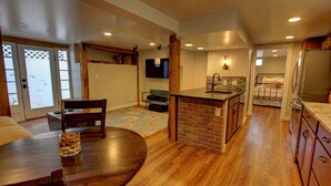 A spacious kitchen with a central island, wooden flooring, and a dining area with a round table and chairs. - Cozy Luxury Remodel, Fantastic Backyard! Walk in 5 minutes to CSU/Old Town (Ft Collins)