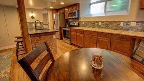 A kitchen with wooden cabinets, a granite countertop, a stainless steel refrigerator, and a dining table with a glass bowl. - Cozy Luxury Remodel, Fantastic Backyard! Walk in 5 minutes to CSU/Old Town (Ft Collins)