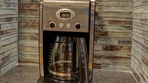 A coffee machine with a digital display and control buttons, placed in a corner with a tiled wall. - Cozy Luxury Remodel, Fantastic Backyard! Walk in 5 minutes to CSU/Old Town (Ft Collins)