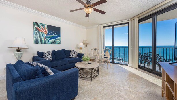 A spacious living area with a large sofa set, a coffee table, and a painting on the wall.