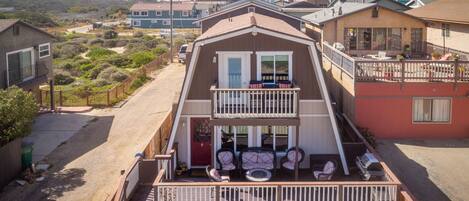 Une maison à deux étages avec un balcon, une allée et une vue sur le quartier environnant.