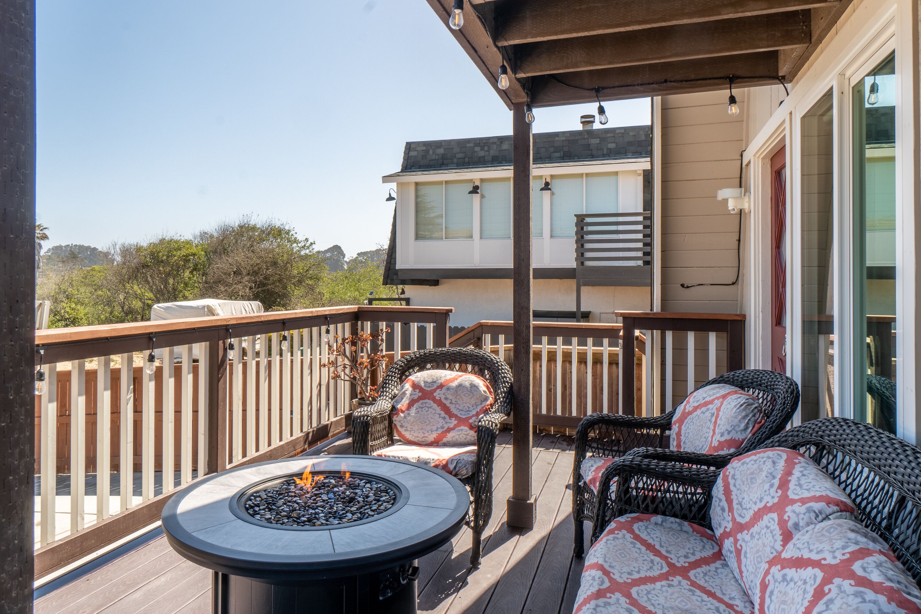 Una terraza con mobiliario exterior, una chimenea y vistas a una casa.