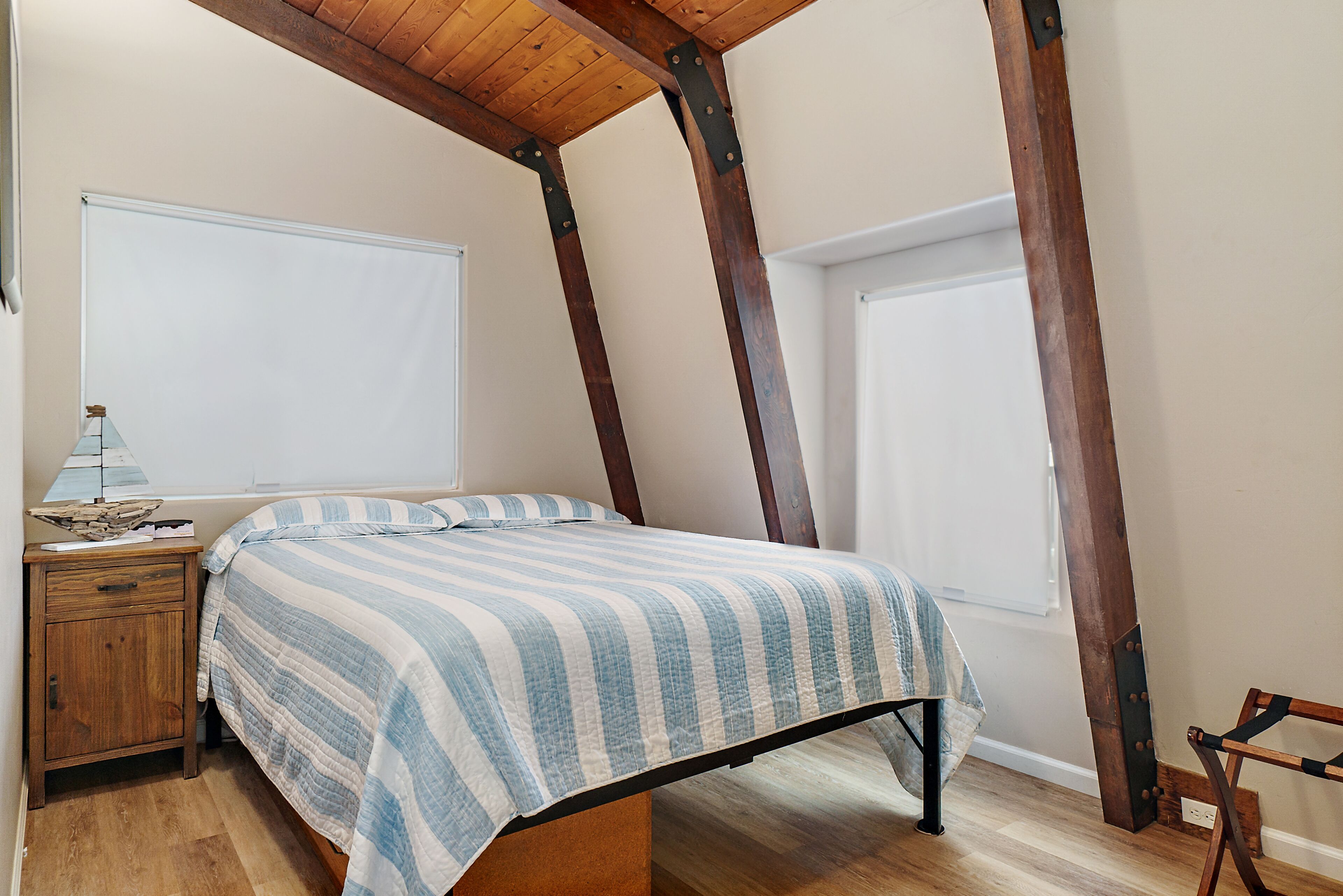 A bedroom with a bed, wooden nightstand, and a window.