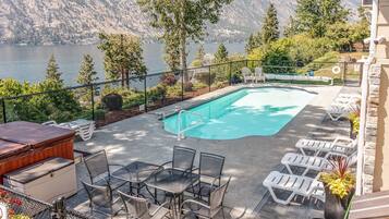 Relax by the serene pool surrounded by lounge chairs and a barbecue area, with breathtaking views of the surrounding mountains and water.