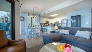 Una sala de estar moderna con un sofá gris, un sillón de cuero marrón y un comedor con sillas blancas y una mesa.