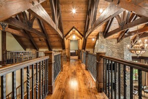 A wooden interior with a high ceiling, wooden beams, and a stone wall.