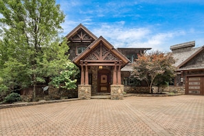A large, rustic-style house with a prominent wooden entrance and stone pillars.