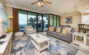 A living room with a sofa, armchair, coffee table, and a dining area with chairs and a table.