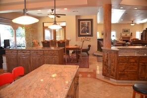 A spacious kitchen with granite countertops, wooden cabinets, and a dining area with chairs and a table.
